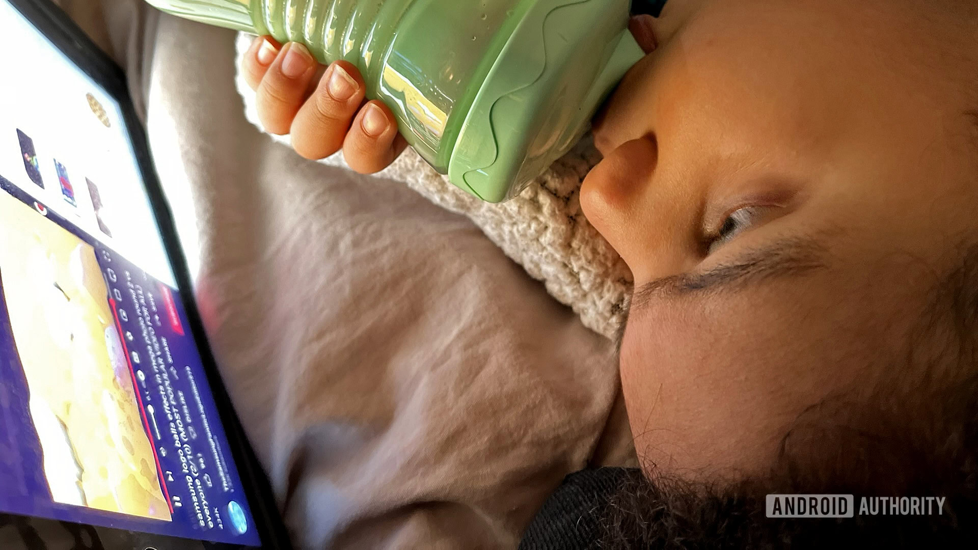 A toddler with a bottle watching YouTube on his iPad