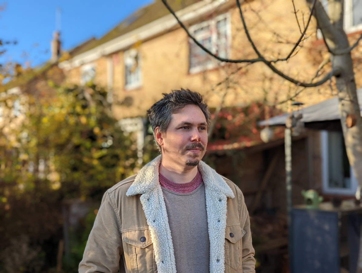 Portrait of man standing outdoors in front of brick house shot on Google Pixel 6 Pro