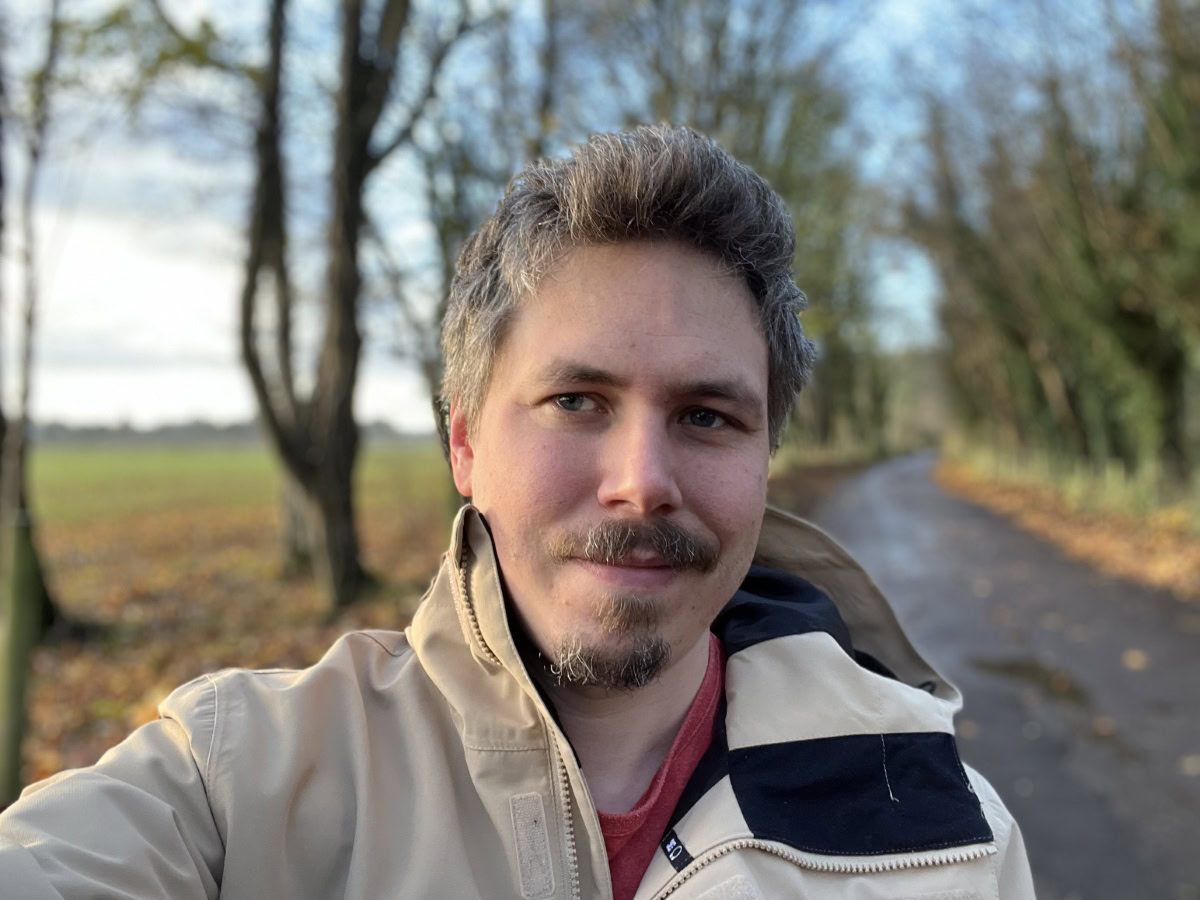 Outdoor selfie on a cold day with trees in the background shot on Apple iPhone 13 Pro Max