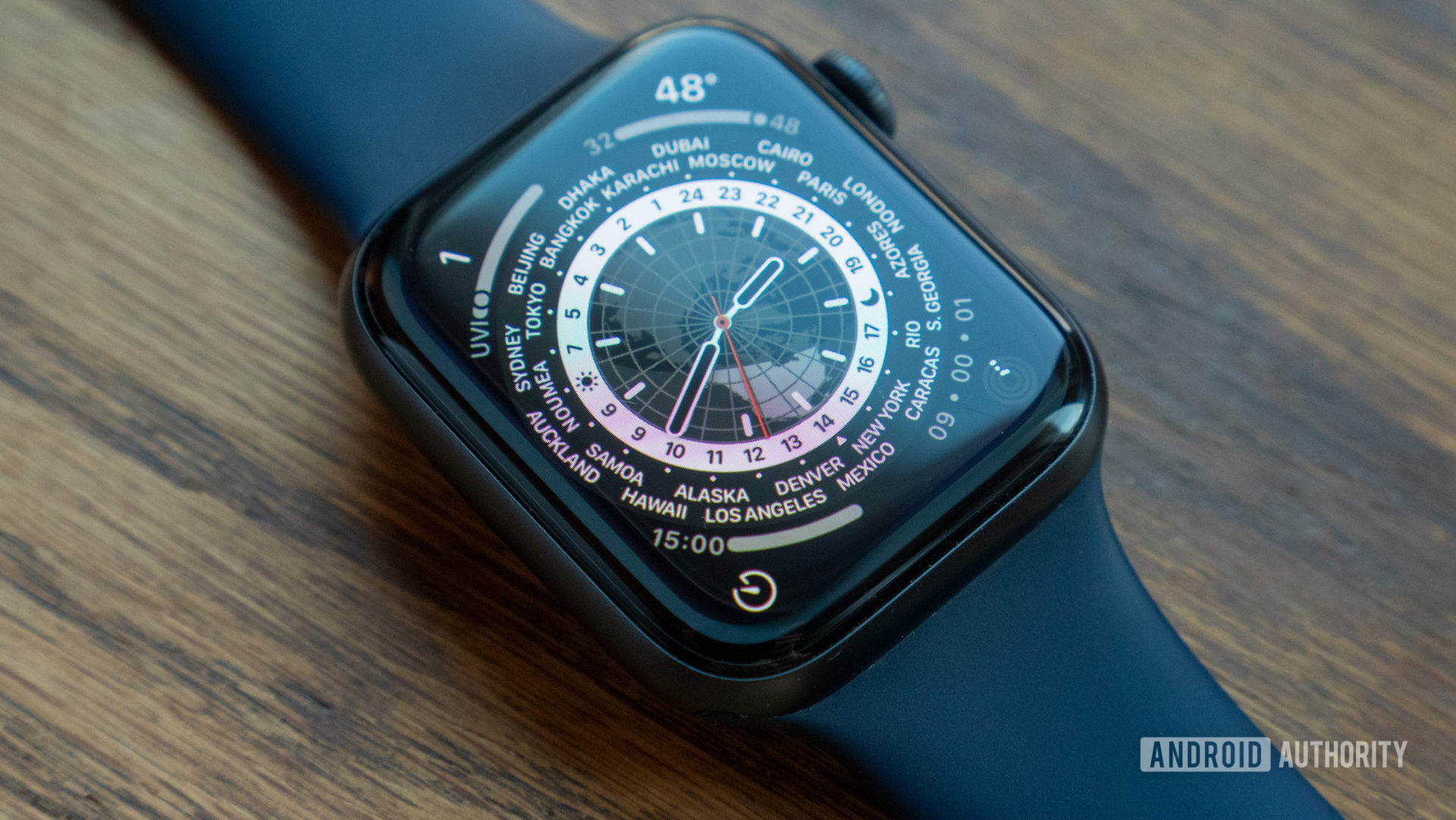 An image of the Apple Watch Series 6 laying on a table showing the World Time watch face on watchOS 8