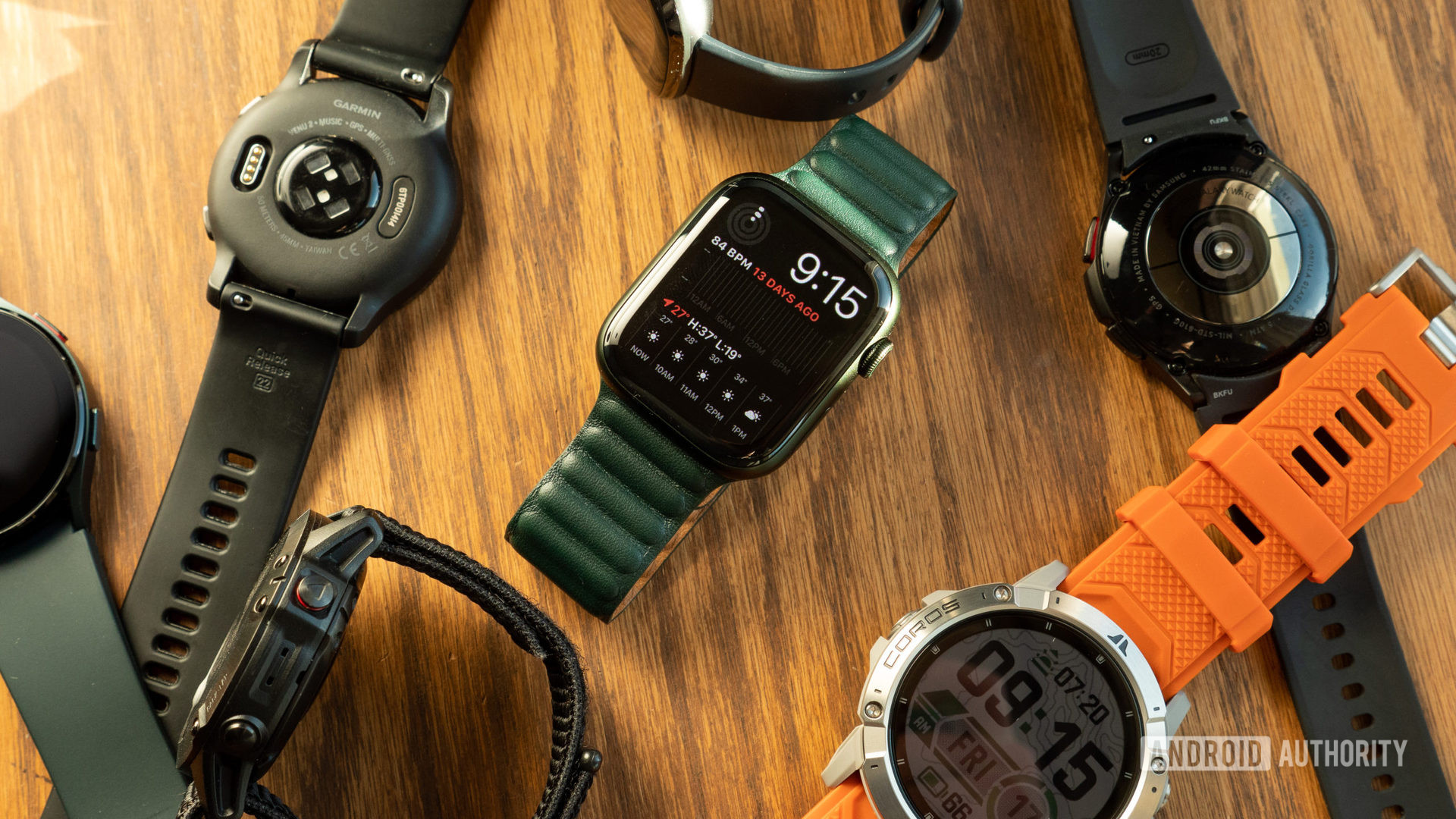 Apple Watch Series 7, Garmin Venue 2, Samsung Galaxy Watch 4, and more smartwatches are lying on a table.
