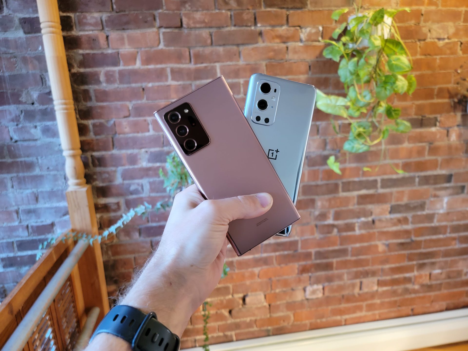 Hand holding the Samsung Galaxy Note 20 Ultra and the OnePlus 9 Pro.