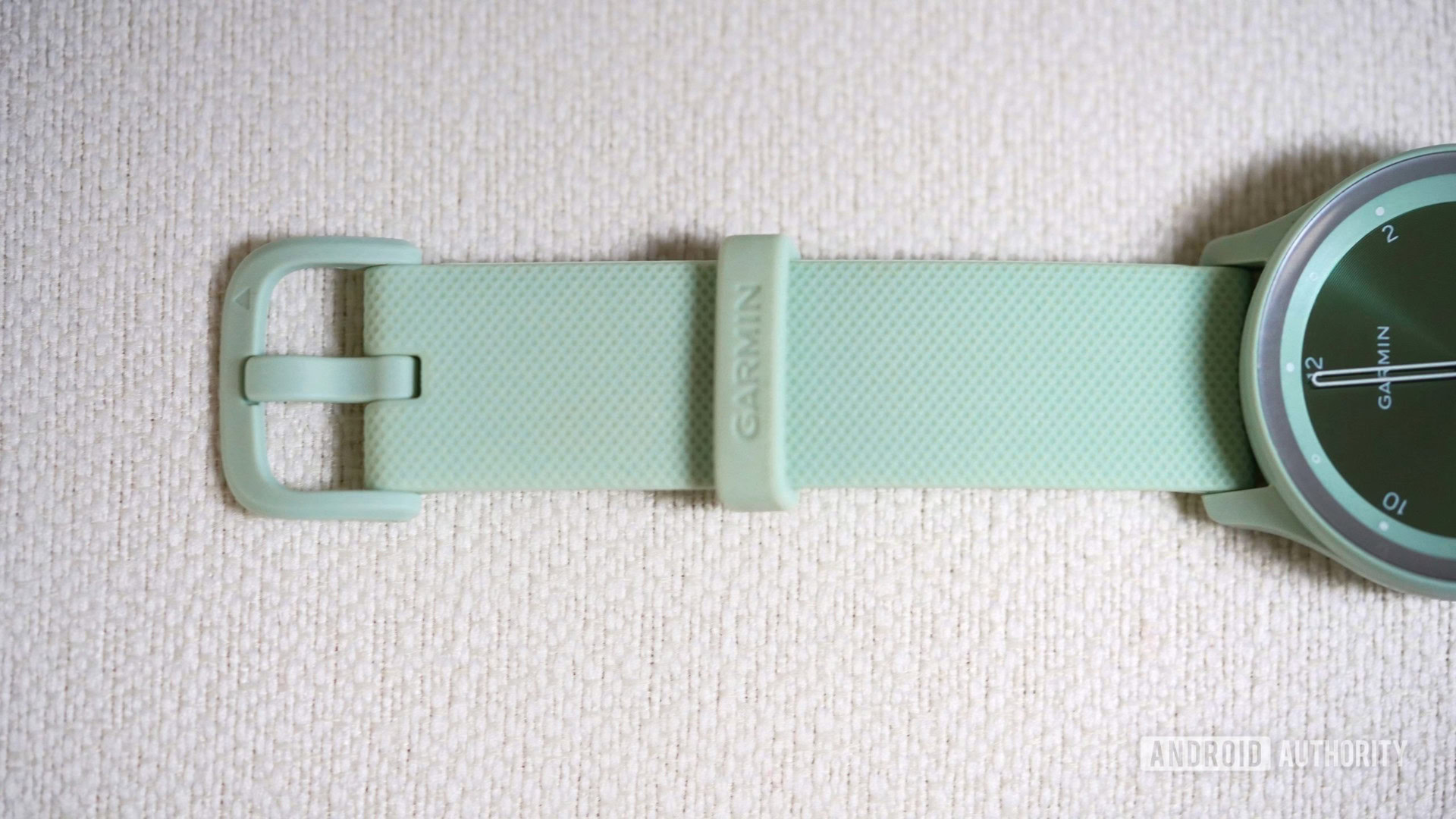 A close up of the Garmin vivomove Sport's band, showing the plastic buckle in soft green.