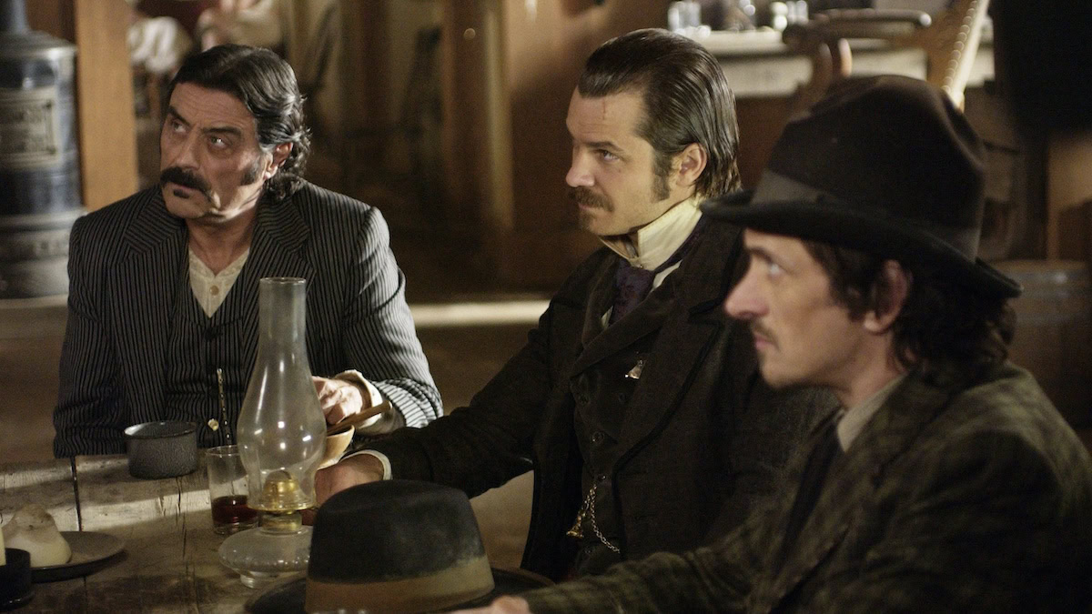 Ian McShane, Timothy Olyphant, and John Hawkes sit in a bar in Deadwood - best HBO Max shows