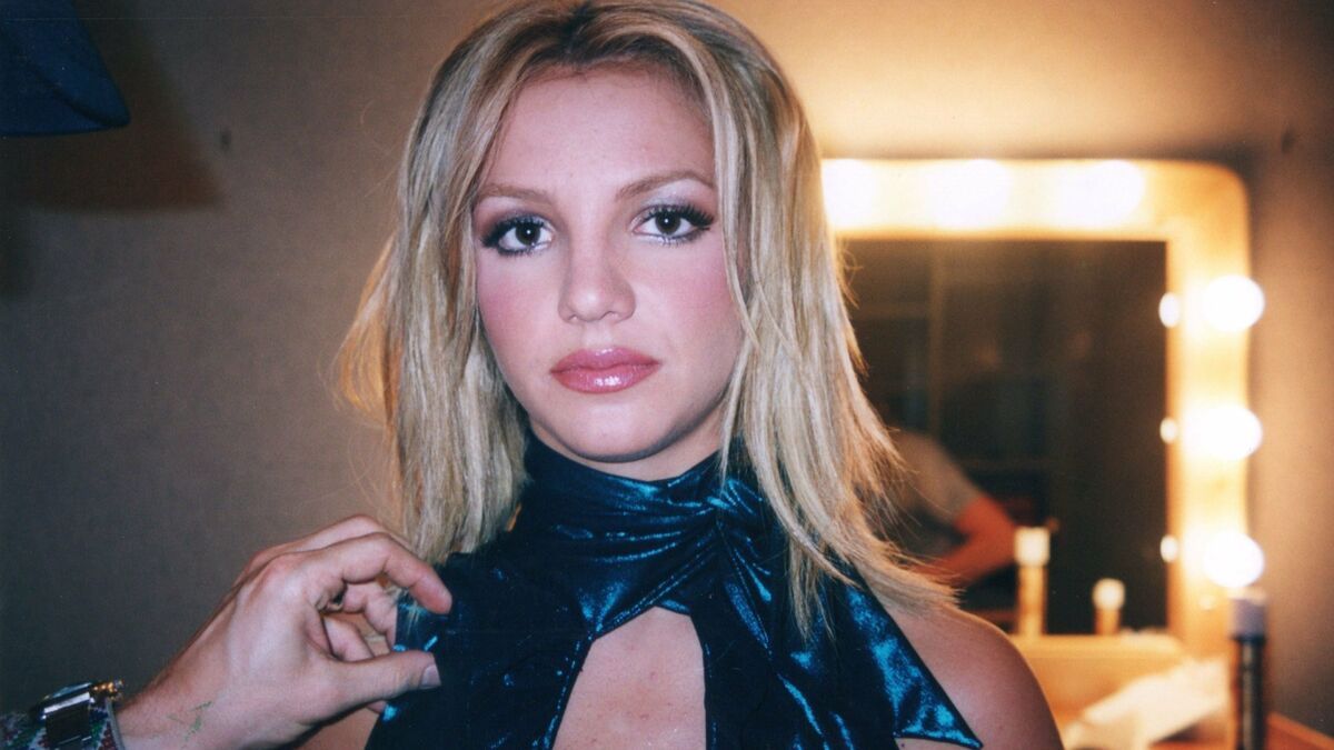 Someone putting a microphone on Britney Spears in Framing Britney Spears — movies like Pam and Tommy
