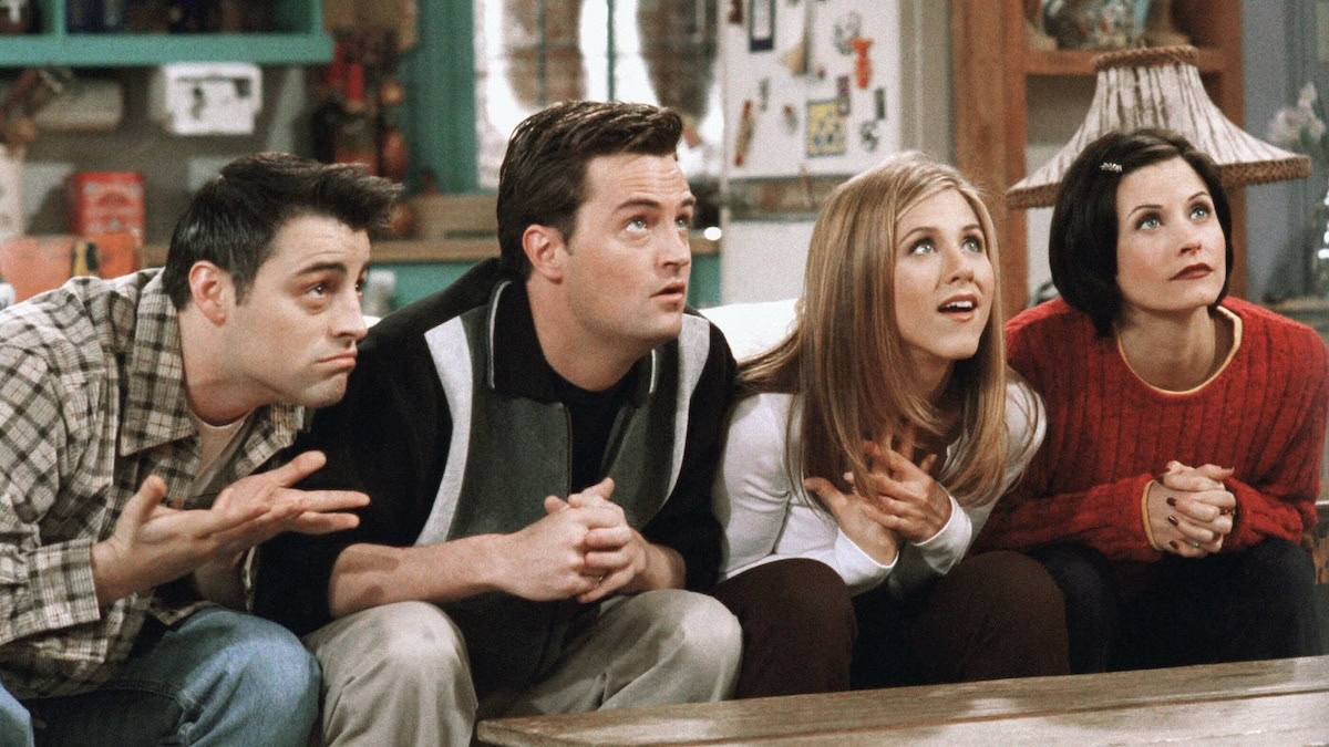 Cast of Friends leaning over a table, playing a game - streaming wars