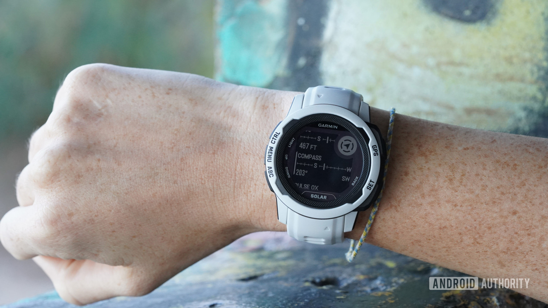 A Garmin Instinct 2S on a user's wrist displays the device's built-in compass.