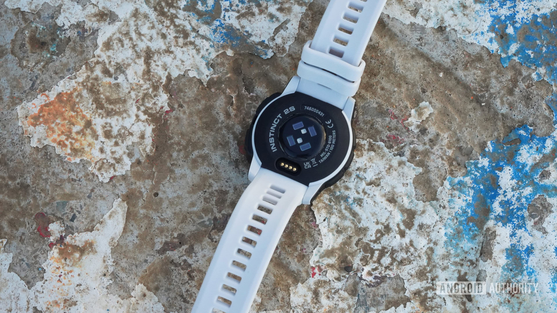 A Garmin Instinct 2S Solar rests face down displaying the device's sensors.