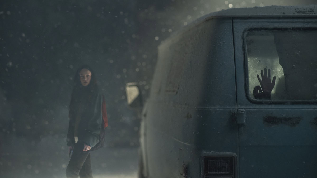 A young woman looks at a van where a hand reaches for help from the back window in No Exit