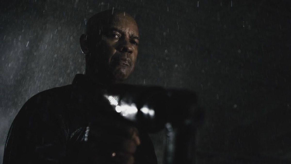 Denzel Washington holding a gun in the rain in The Equalizer — movies like Reacher