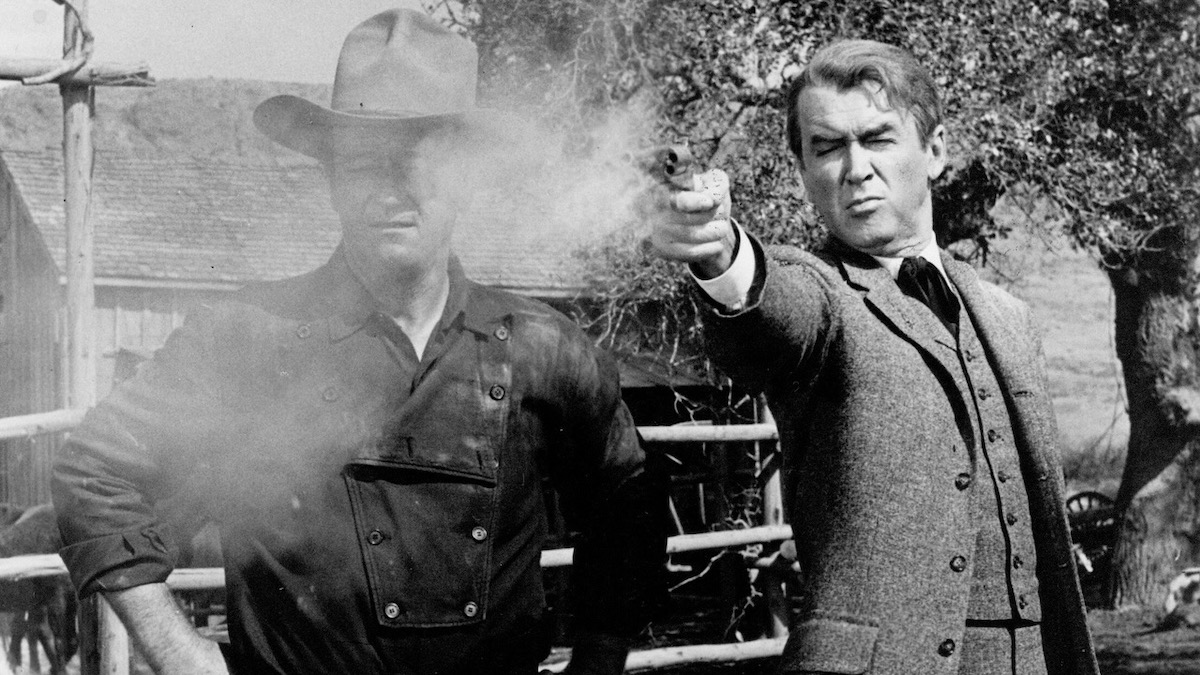 Jimmy Stewart fires a gun next to John Wayne in The Man Who Shot Liberty Valance