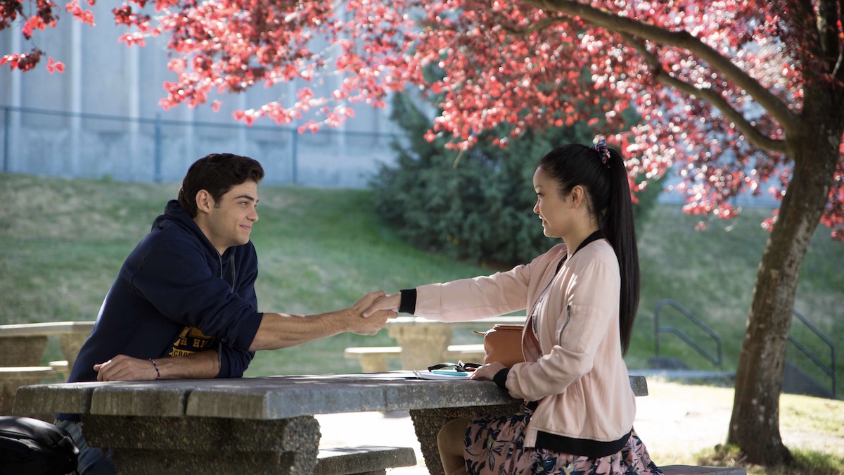 Lana Condor and Noah Centineo shake hands at a picnic table in To All the Boys I've Loved Before - best romance movies on netflix