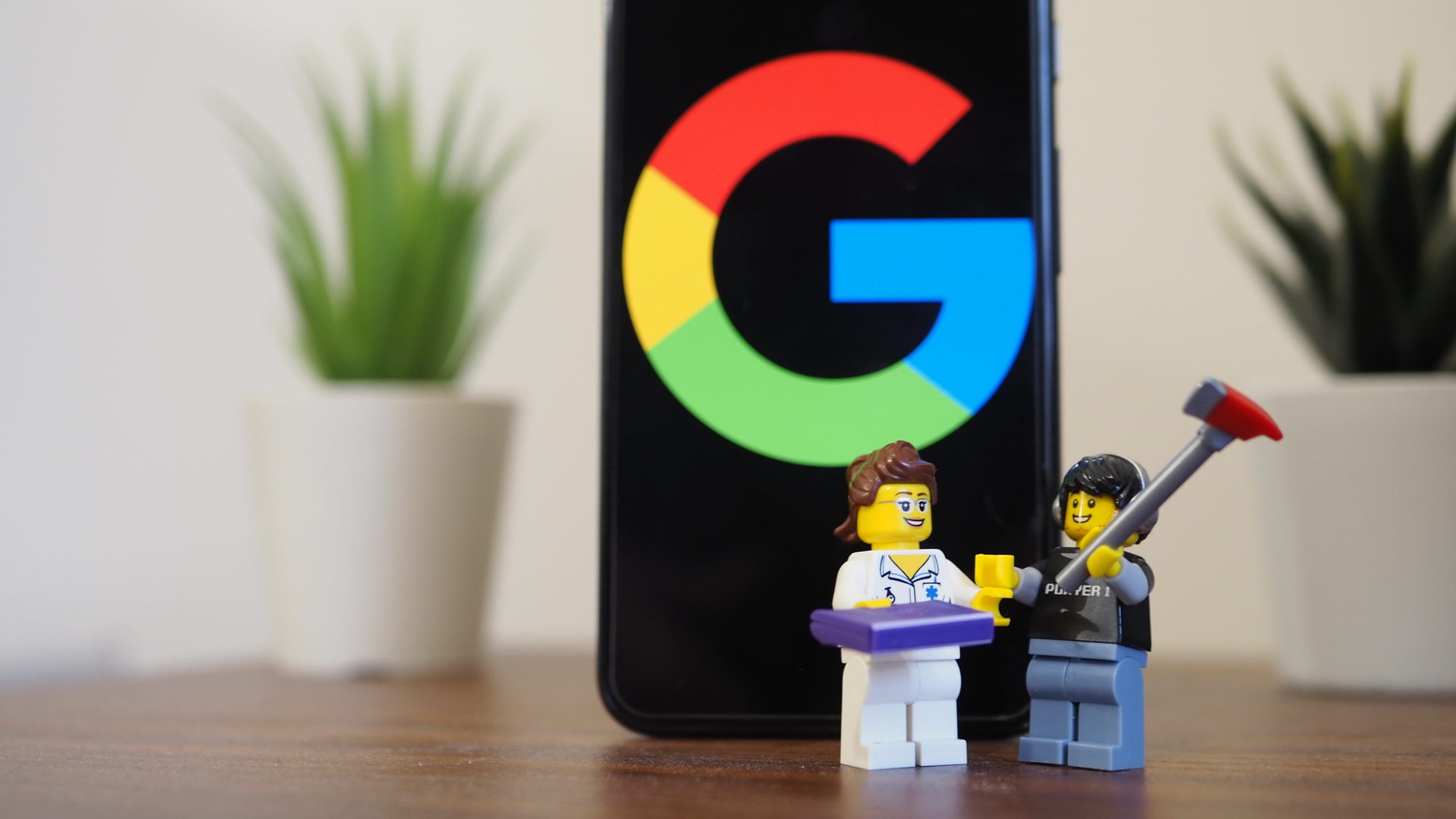 Google Pixel 5 on a table showing Google logo with two lego figurines in front of it