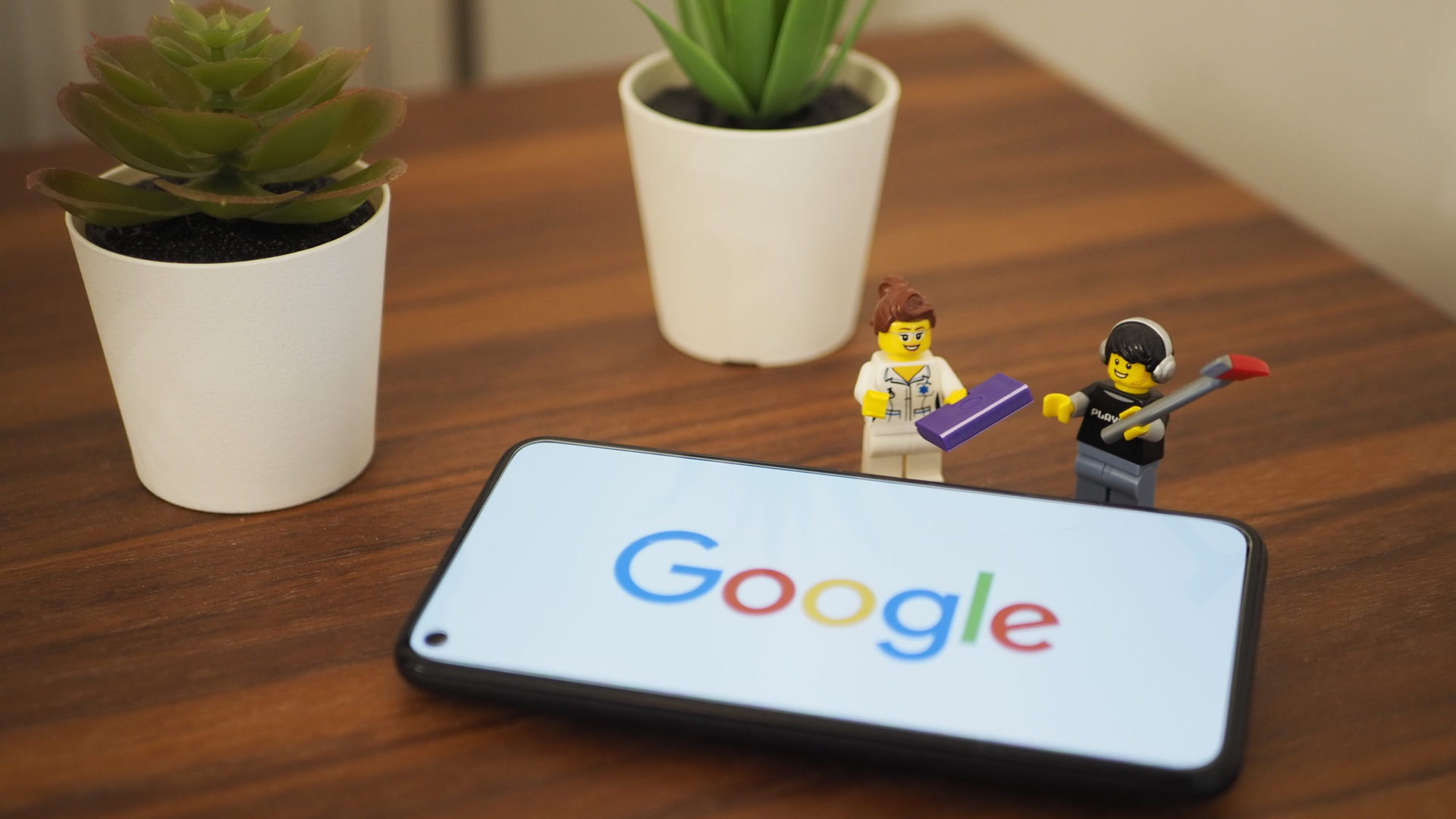 Google Pixel 5 on a table with full Google logo with two lego figurines