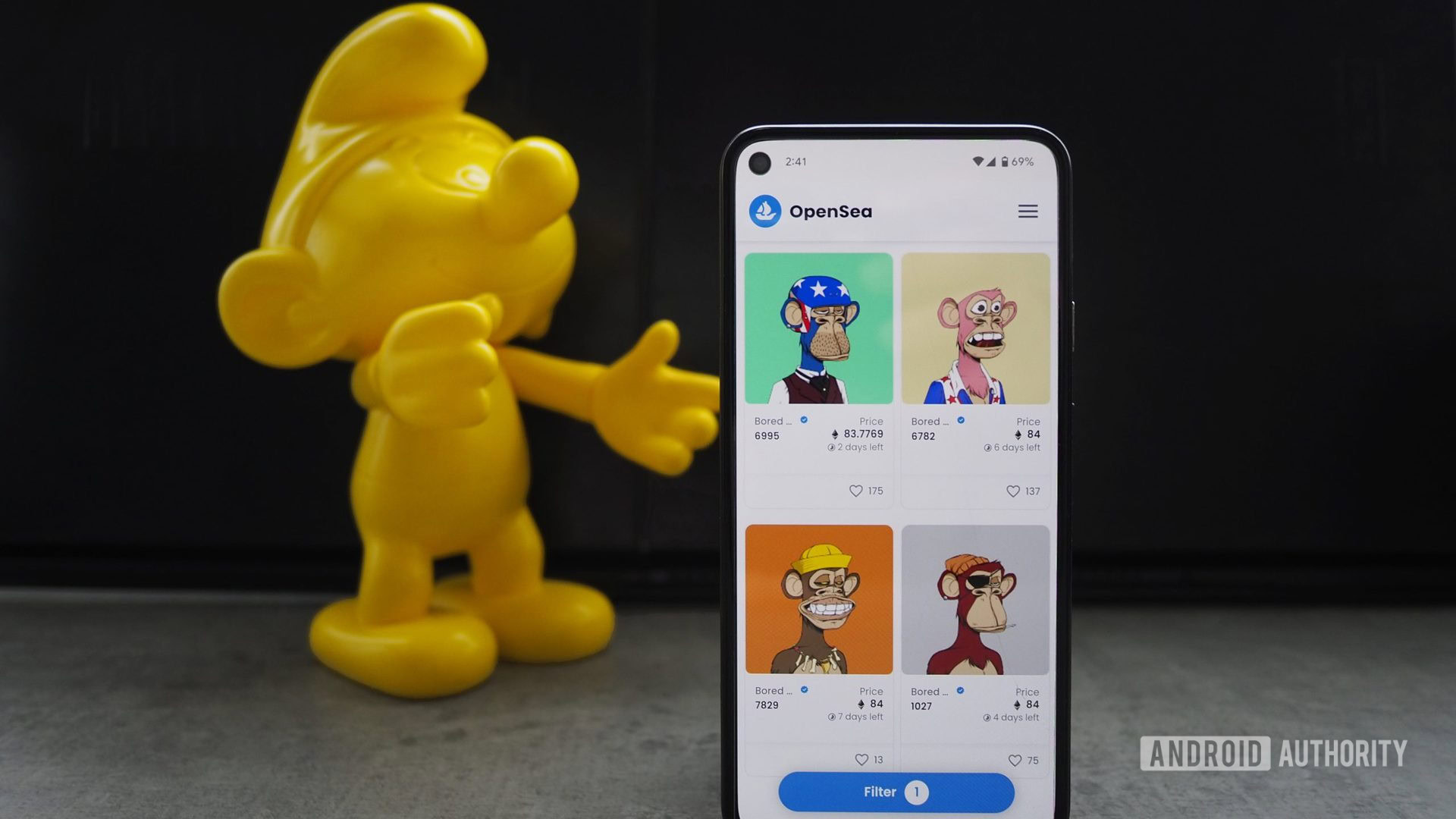 Opensea BoredApe NFTs shown on a Pixel 5 with a yellow smurf further in the background
