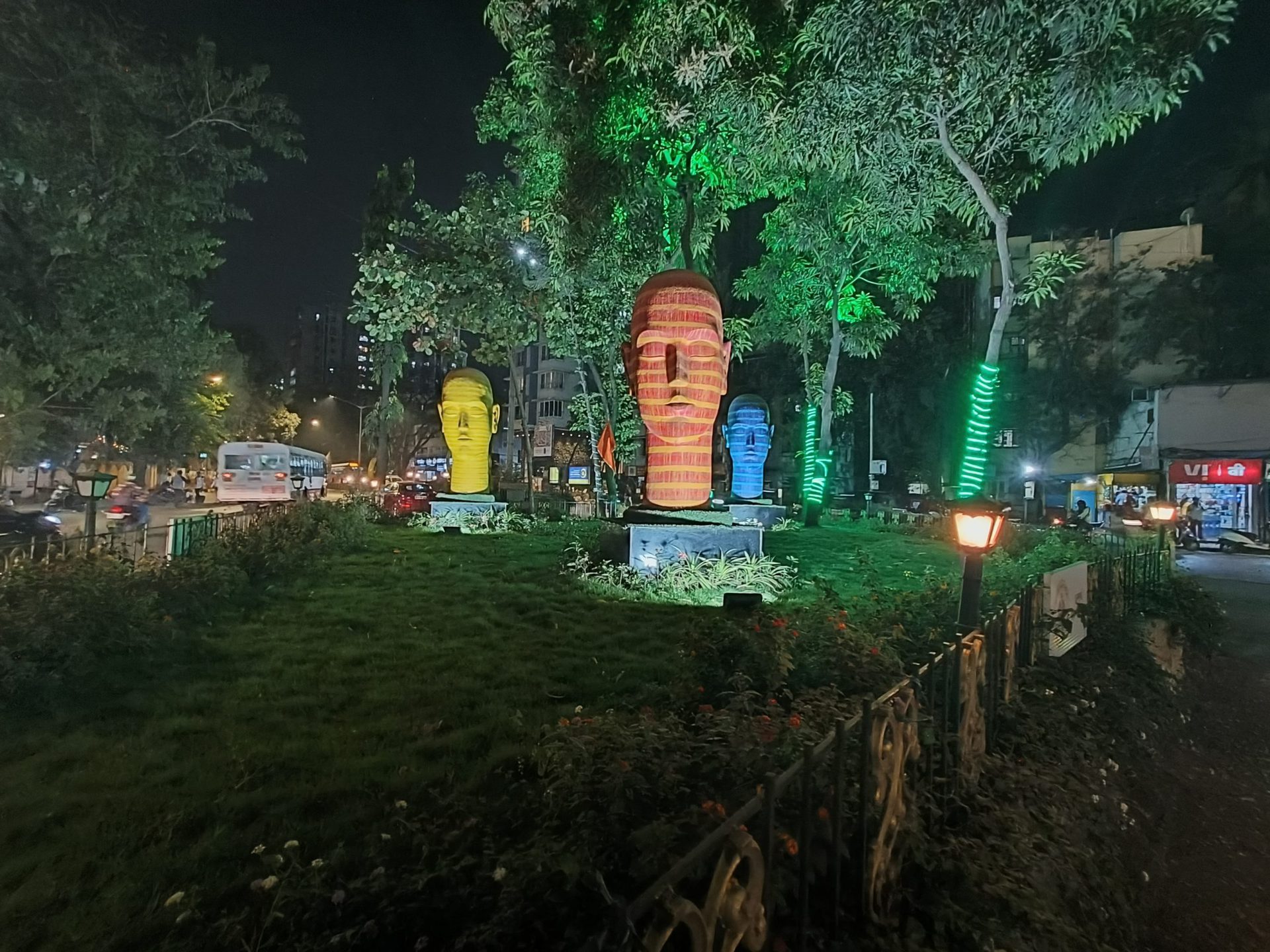 oppo reno 7 pro camera sample ultrawide with night mode of colorful head sculptures in a park.
