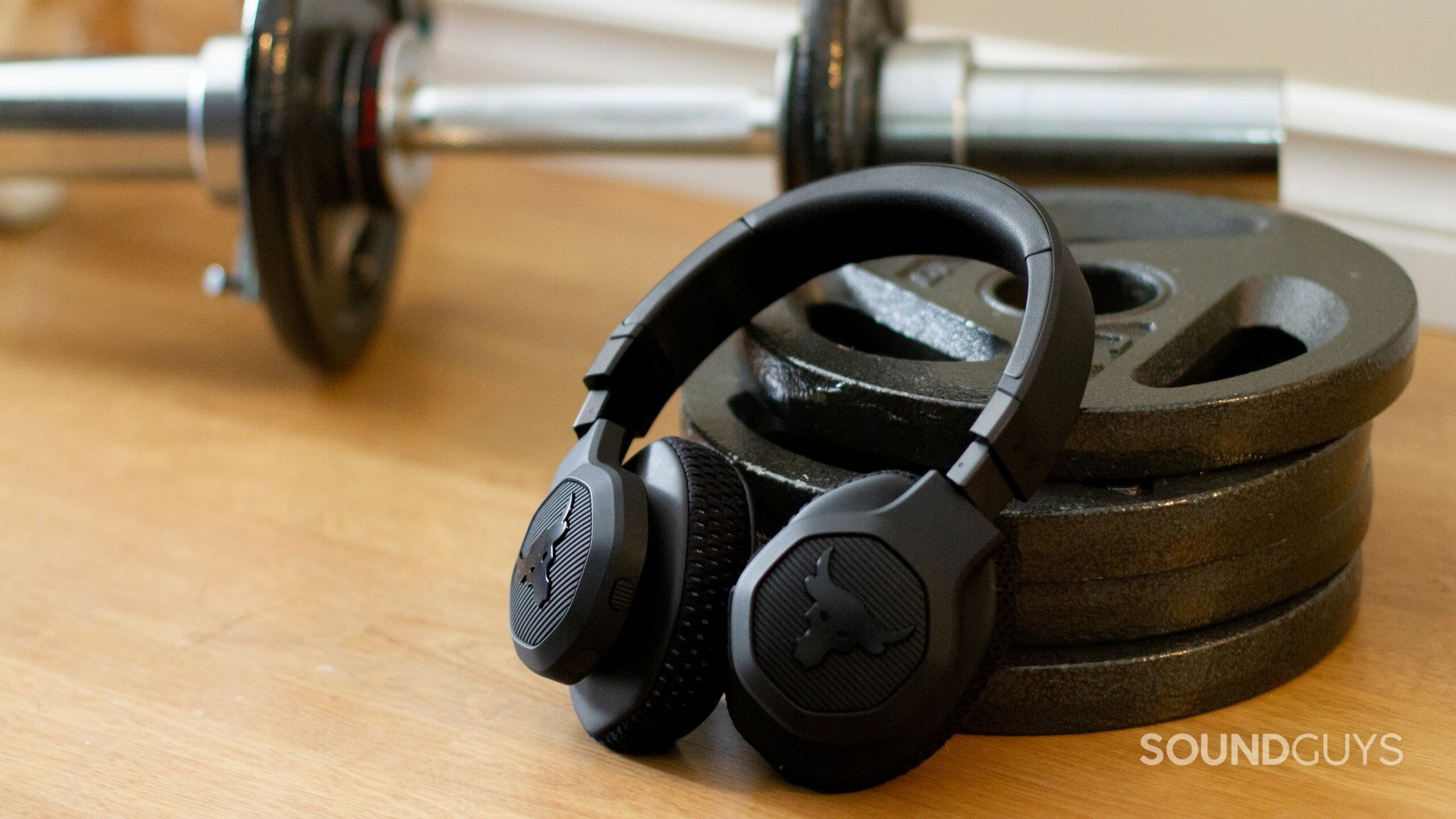 UA and JBL's Project Rock headphones leaning against weights