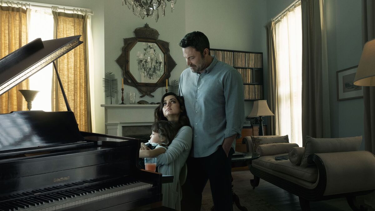 Ben Affleck stands behind Ana de Armas and their son at a piano in Deep Water