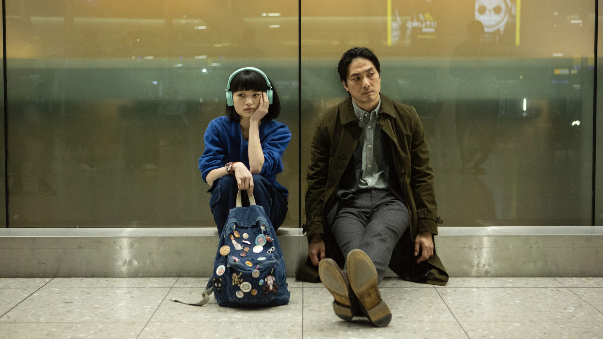 Taki (Aoi Okuyama) and Kenzo Mori (Takehiro Hira) sit on the floor in Heathrow Airport in Giri/Haji - best british crime shows on netflix