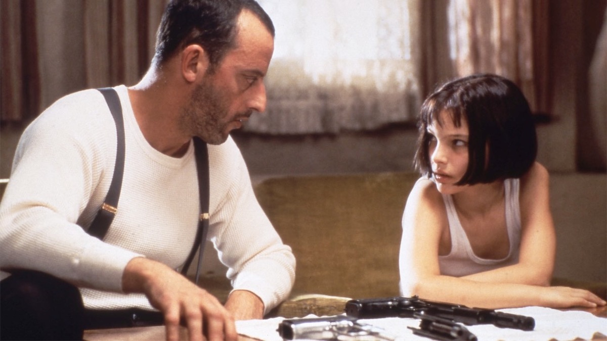 Jean Reno and Natalie Portman at a table covered in guns in Léon The Professional - movies leaving Netflix