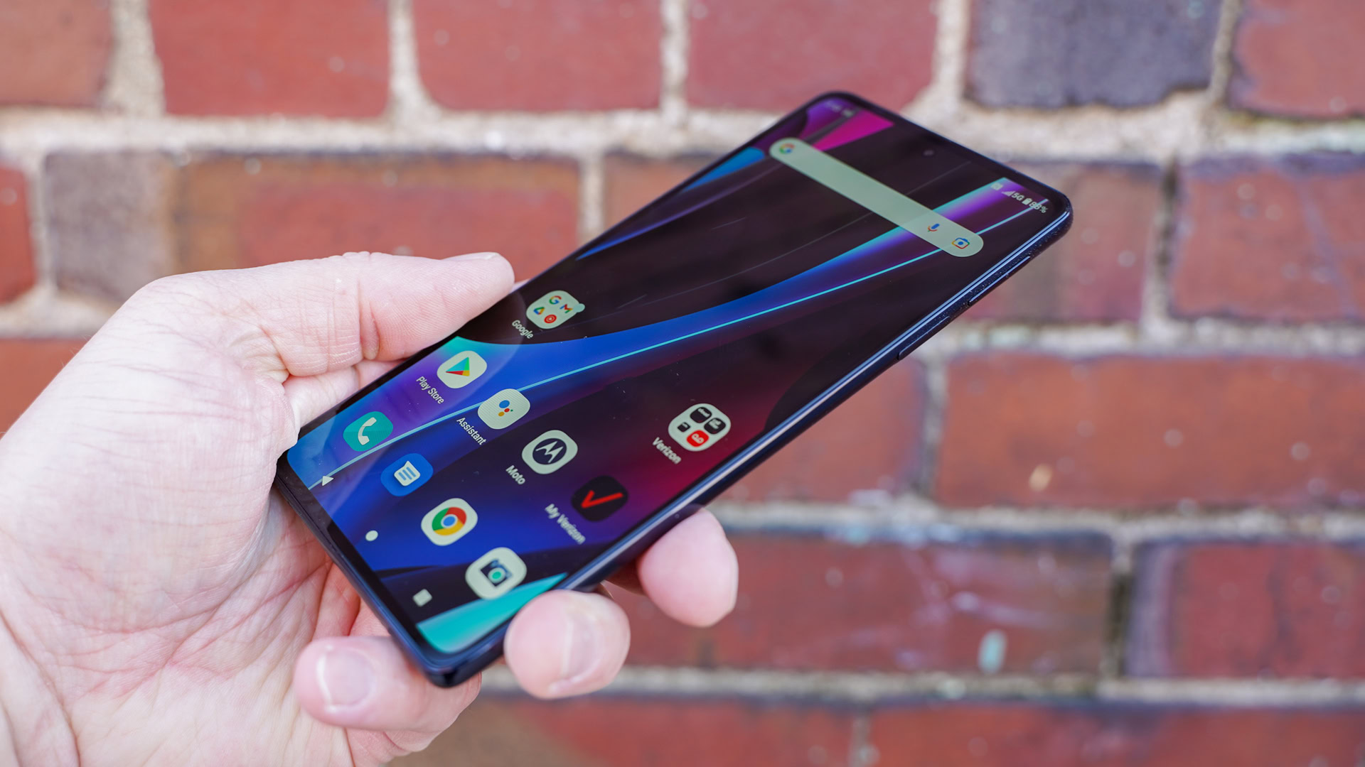 Motorola Edge Plus 2022 display angled in hand against brick