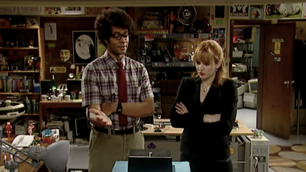 Richard Ayoade and Katherine Parkinson stand together looking at a computer in The IT Crowd - best british shows on Netflix