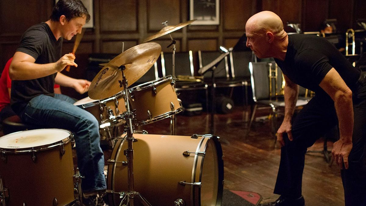 Miles Teller sits at a drum kit, instructed by J. K. Simmons in Whiplash - best movies like CODA