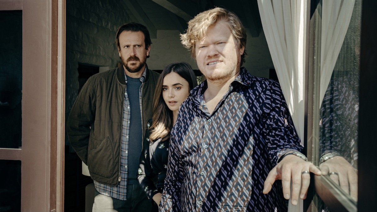 Lily Collins, Jesse Plemons, and Jason Segel stand at an open door looking out in Windfall