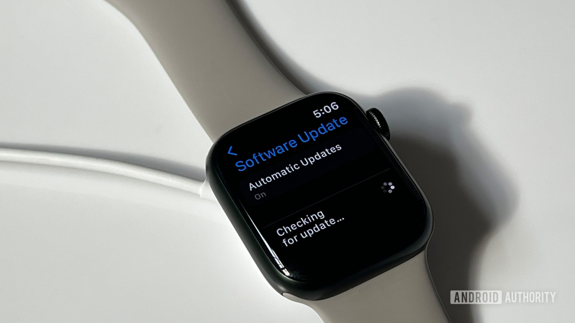 An Apple Watch Series 7 checks for available software updates while resting on its charger.
