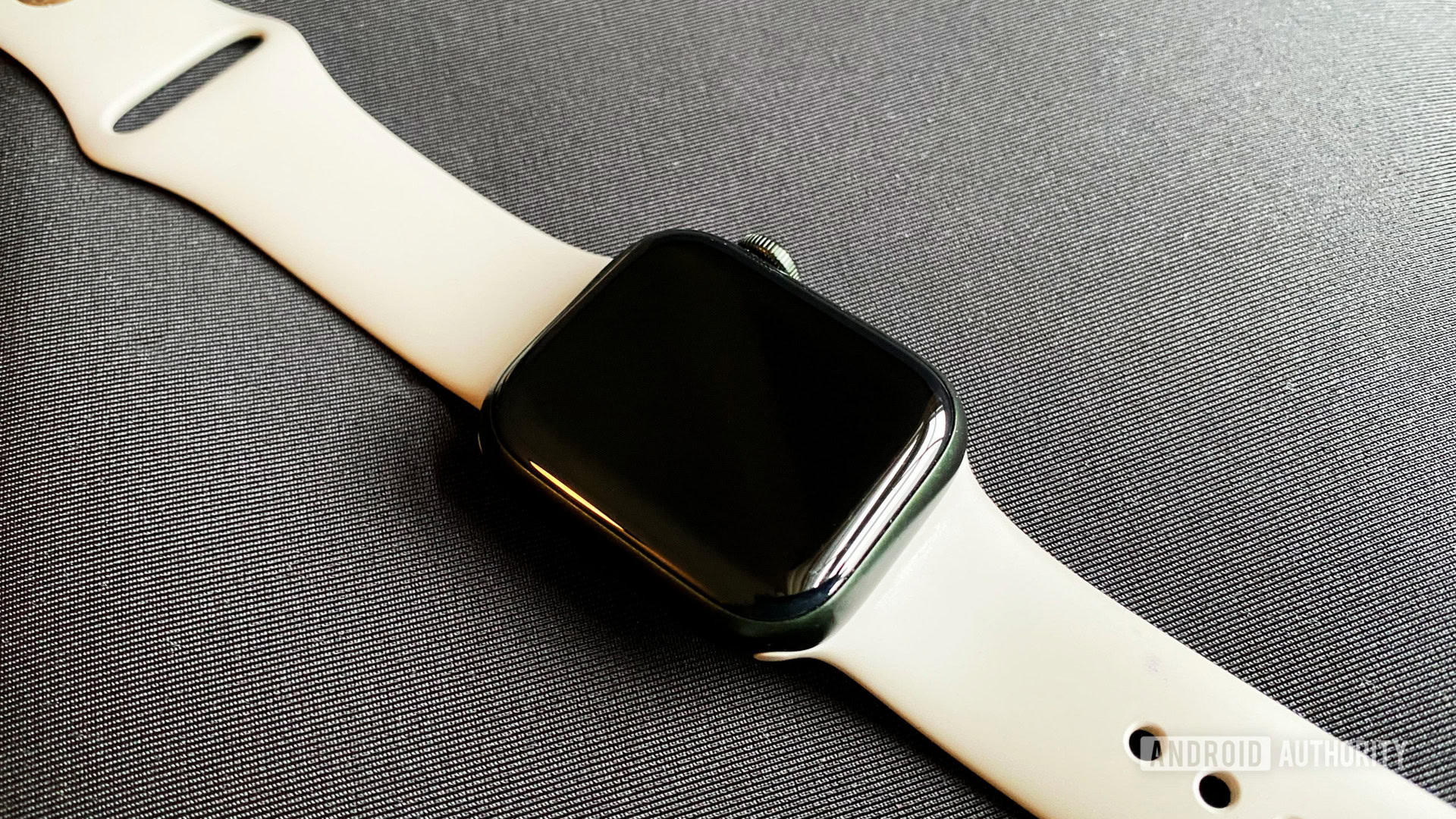 An Apple Watch Series 7 rests on a black mat with an inactive screen.