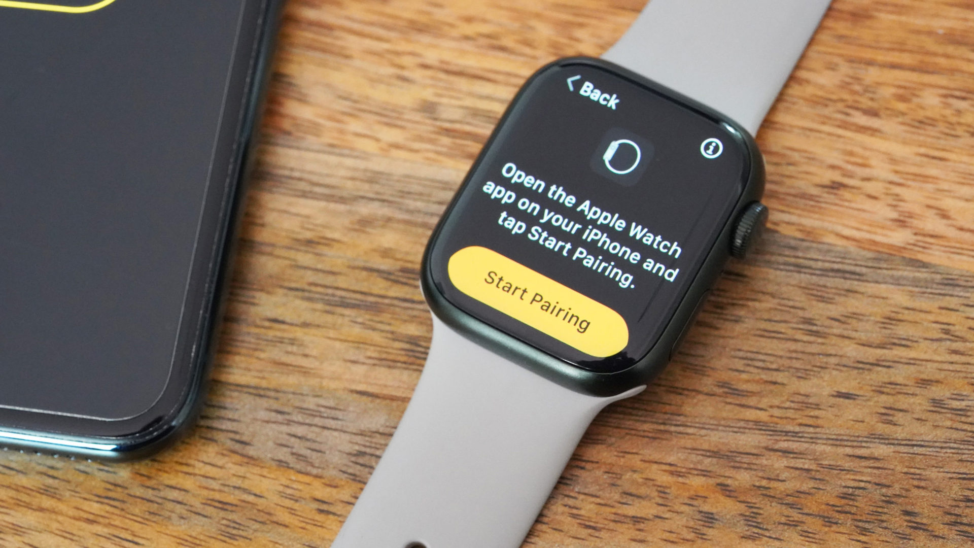 Apple Watch Series 7 berada di samping iPhone dengan instruksi pemasangan di layar.