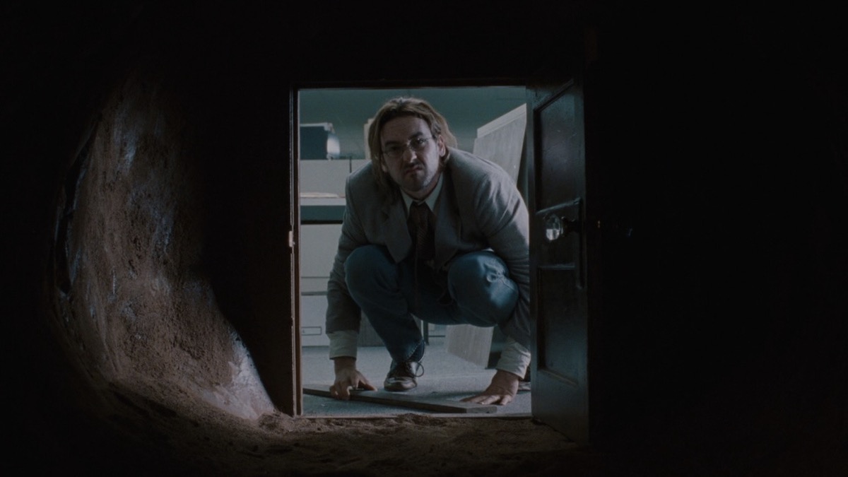 John Cusack looks through a small door into a tunnel in Being John Malkovich