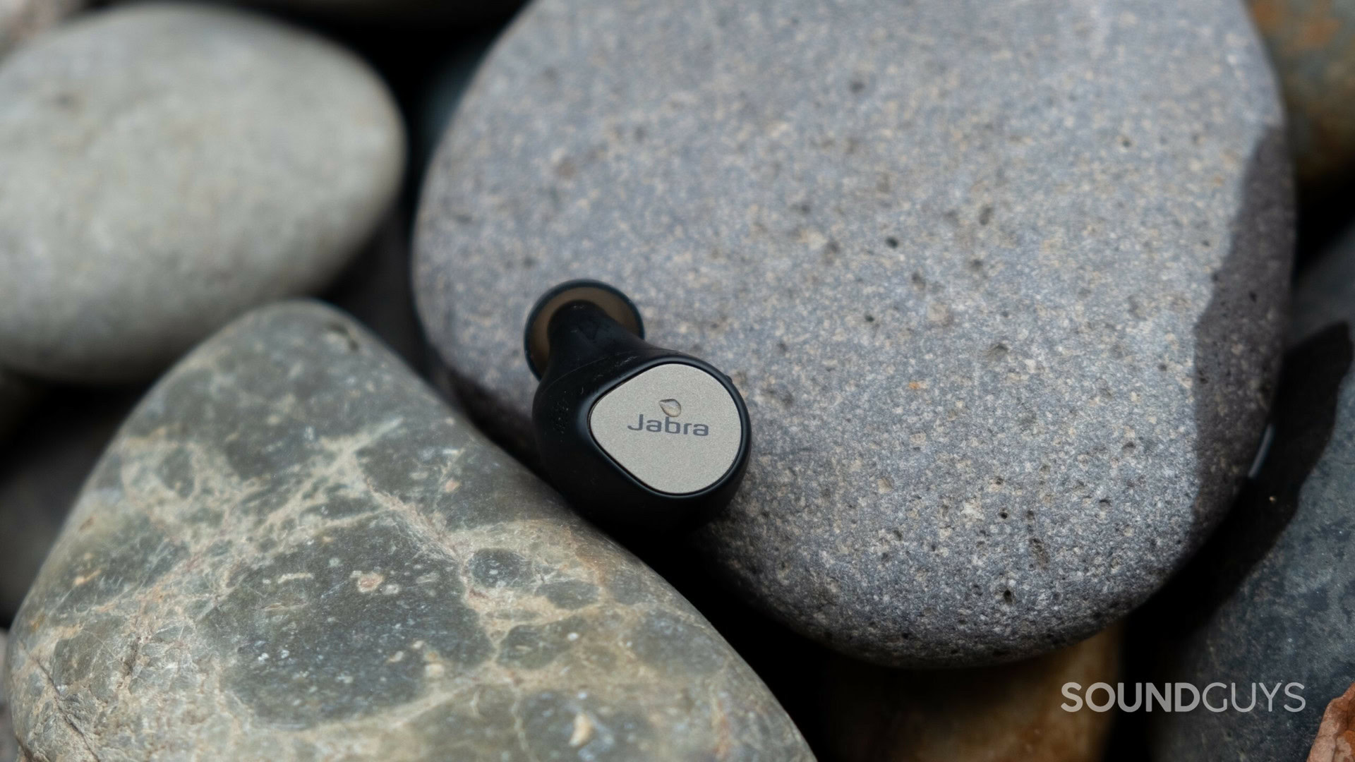 Jabra Elite 7 Pro earbud resting on pile of rocks