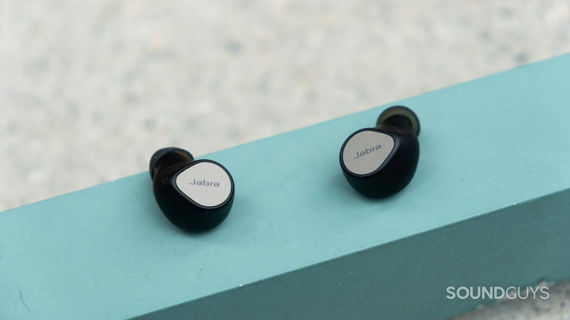 The Jabra Elite 7 Pro earbuds outsie on a pale blue surface.