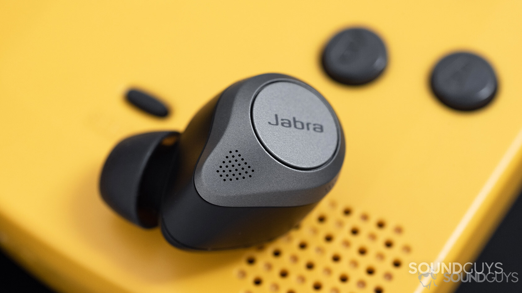 The Jabra Elite 85t noise canceling true wireless earbuds microphone holes next to a Gameboy Color speaker grill.