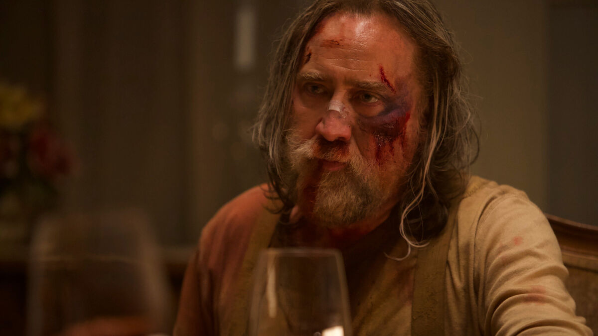 A bloodied Nicolas Cage sits at a dinner table in Pig