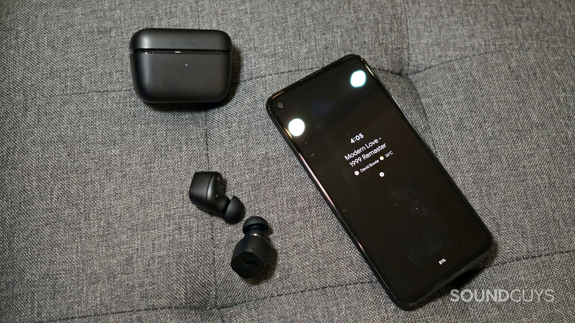 Sennheiser CX True Wireless headphones and case next to a phone.