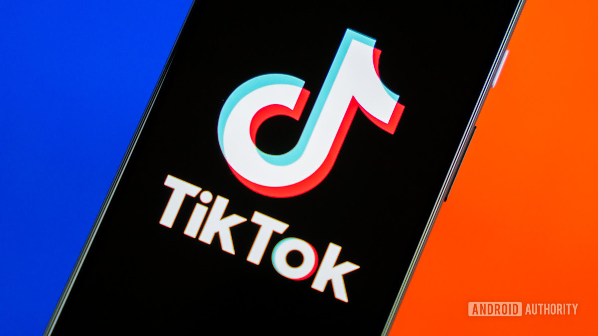 A stock photo of the TikTok logo shown on a darkened smartphone screen in front of a blue and red background.