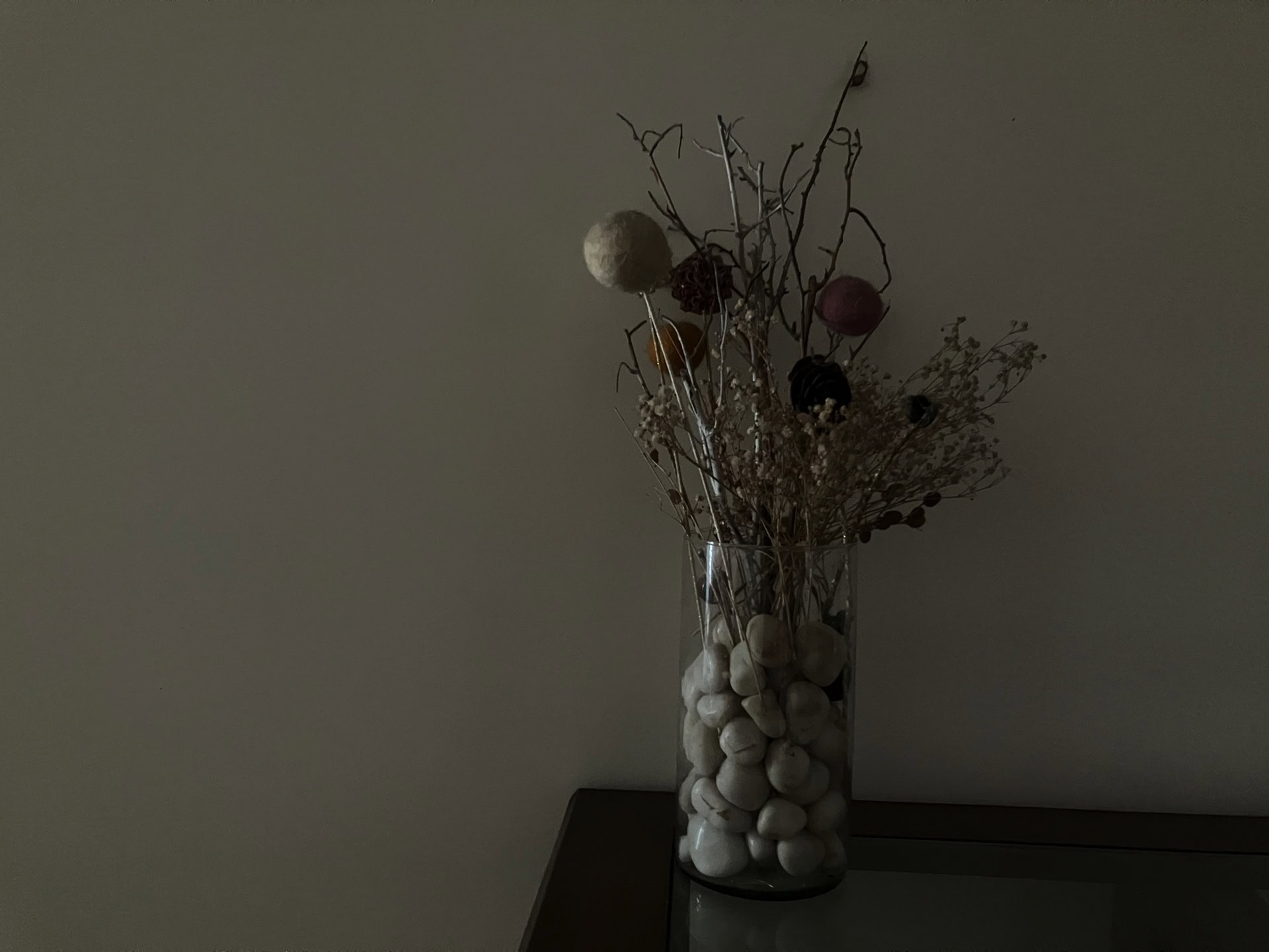 low light image of dried flowers and pebbles in a vase shot on an iPhone SE