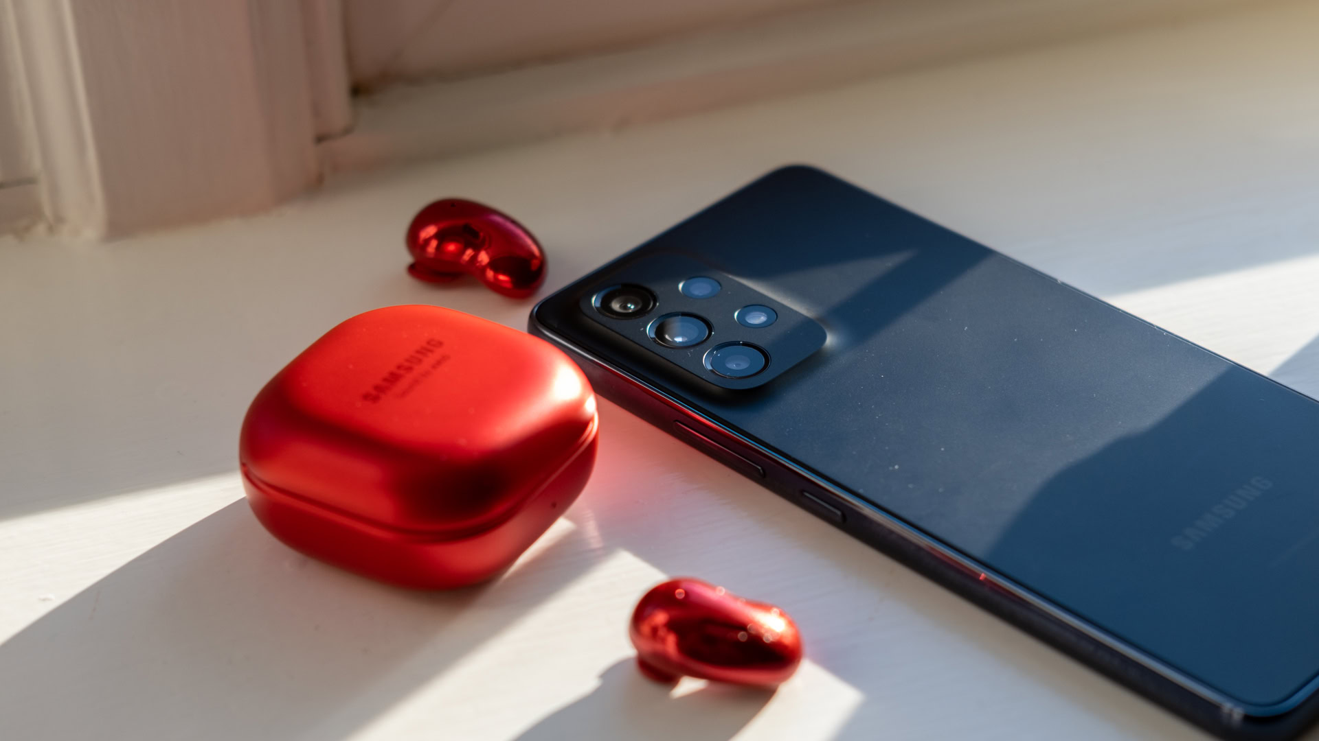 samsung galaxy a53 buttons next to red galaxy buds and case