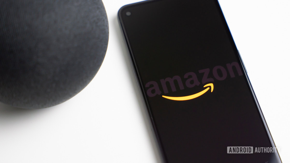 Amazon logo on phone next to Echo Dot speaker