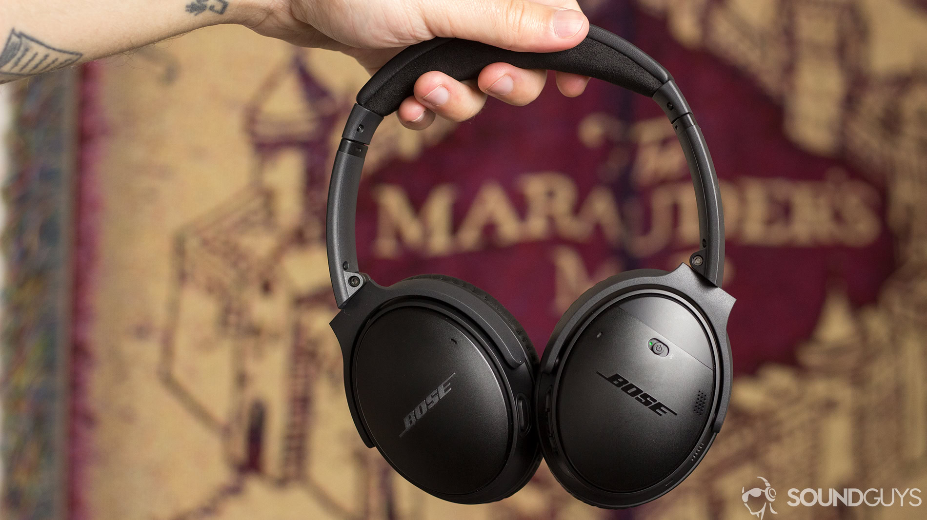 A man's hand holds the Bose QC 35 II noise cancelling wireless headphones.