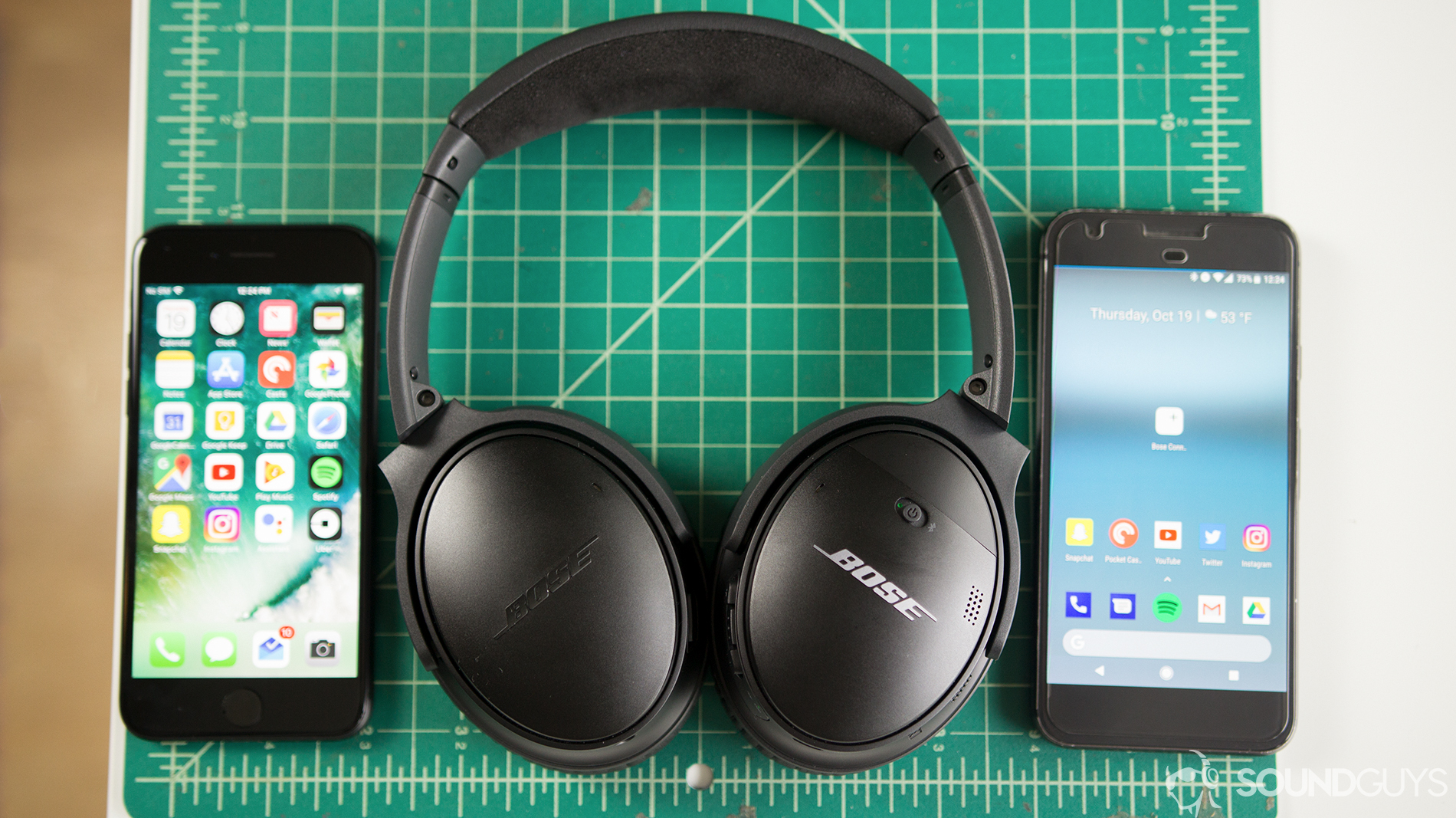 The Bose QuietComfort 35 II on a gridded surface next to two smartphones.