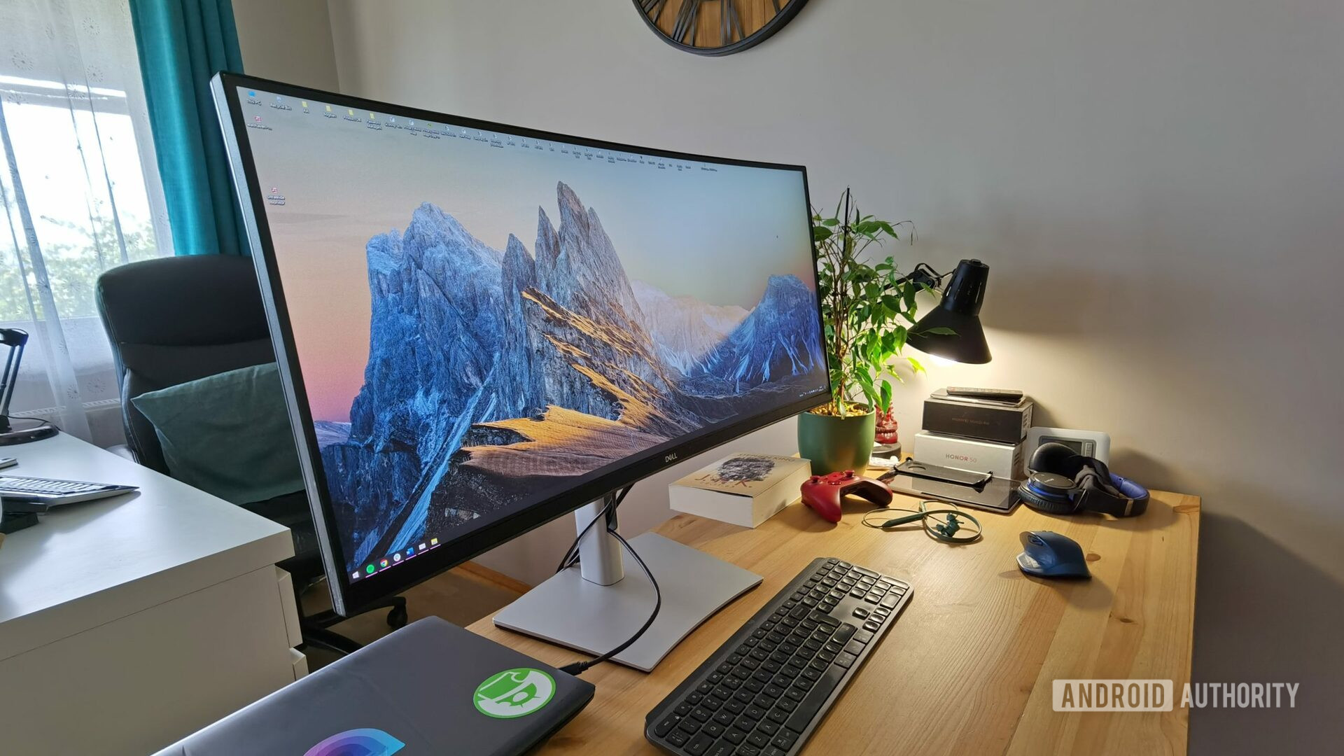 Dell P3421W ultrawide monitor on a desk with keyboard, light, and other desk accessories.