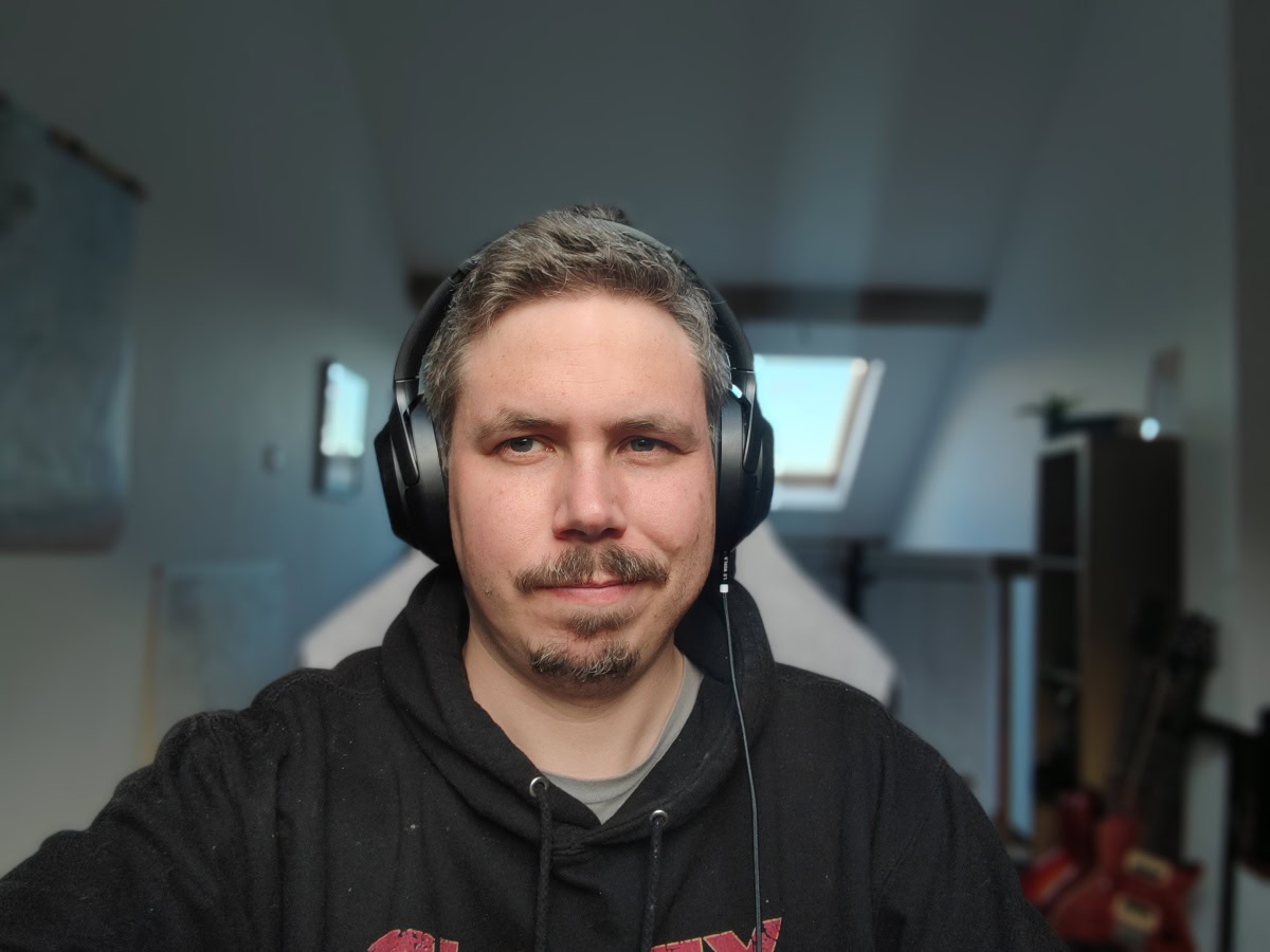 Honor Magic 4 Pro camera sample selfie indoors of a man wearing a black logo hoodie and headphones.
