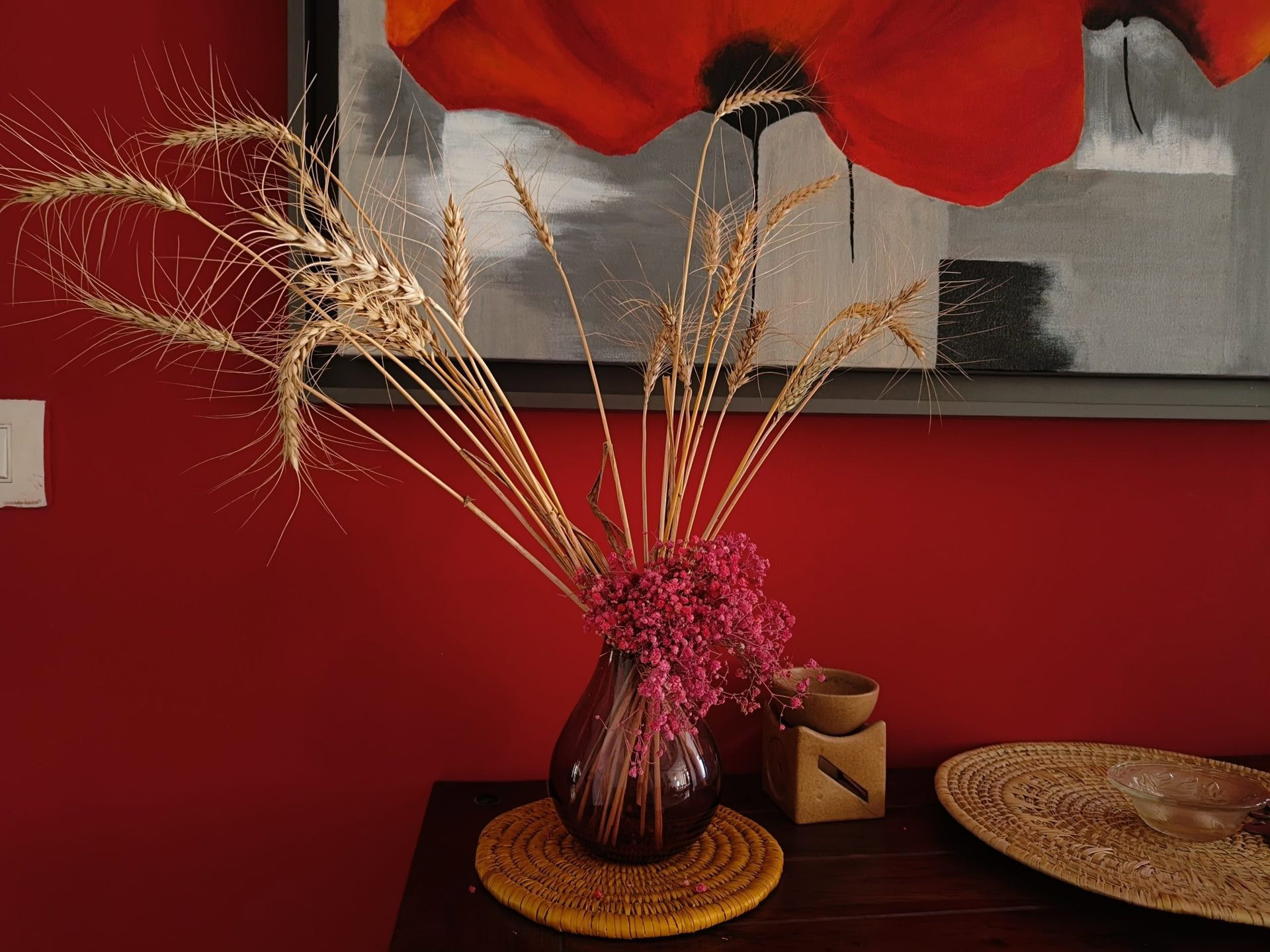 OnePlus 10R camera sample low light indoor glass vase on a table with grasses and dried flowers, against a red wall.