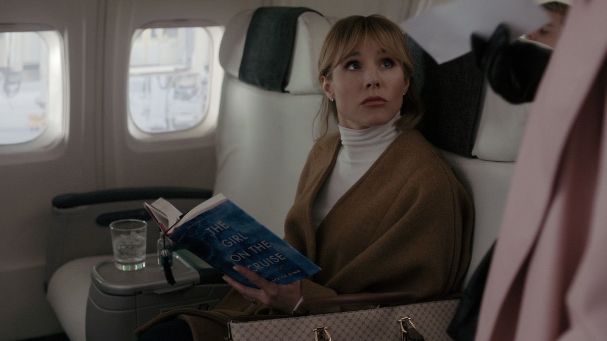 kristen bell reads a book on a plane in The Woman Across the Street from the Woman in the Window - shows like the flight attendant
