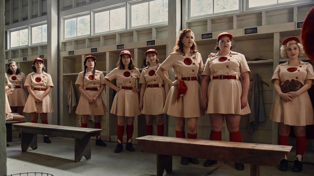 Several women in baseball uniforms stand in the locker room in the A League of Their Own - New on Amazon Prime Video