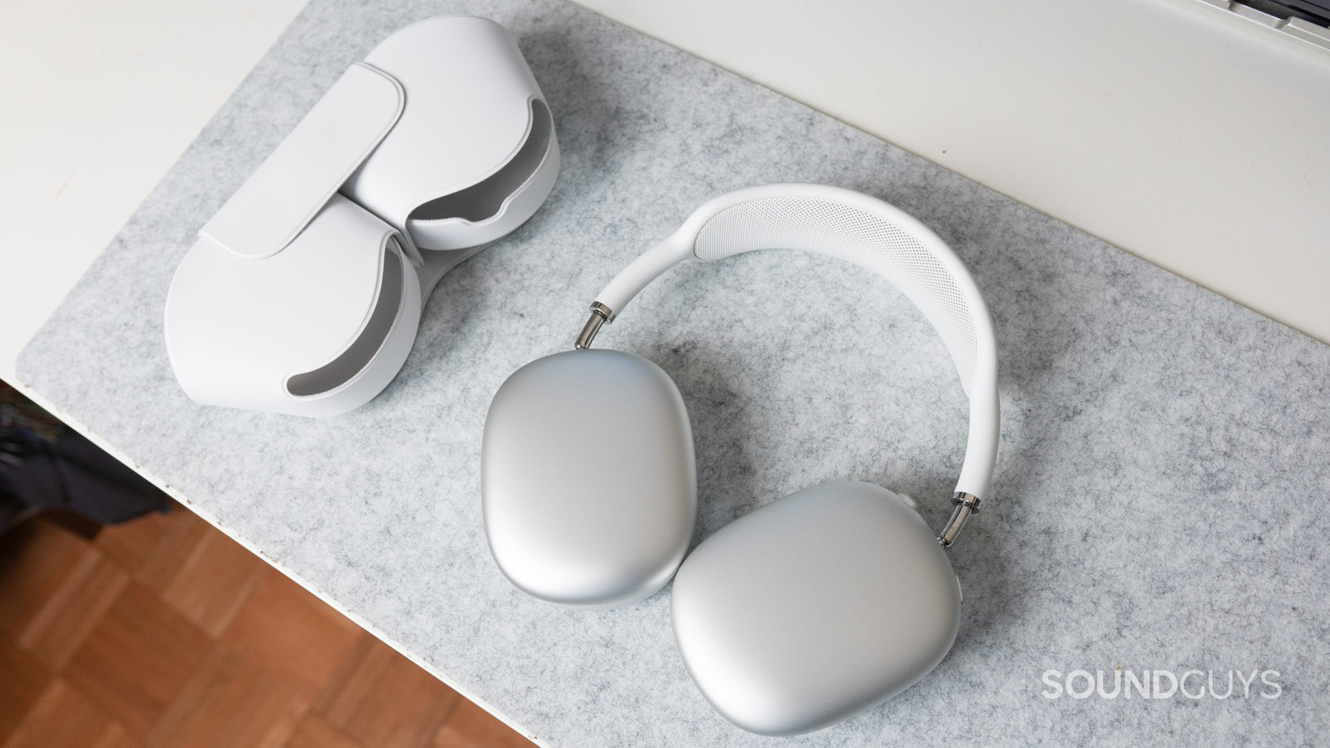 The Apple AirPods Max and their smart case on a white desk.