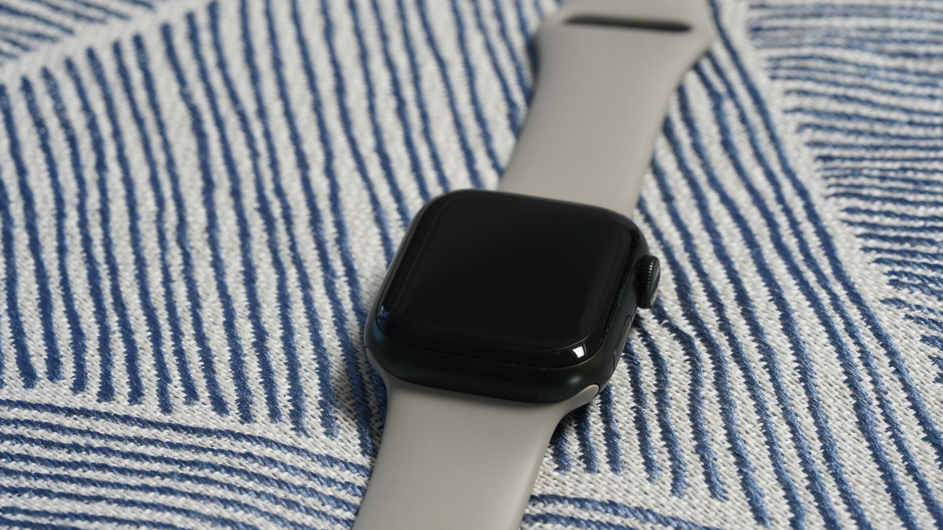 An Apple Watch Series 7 rests on a blue and gray patterned chair.